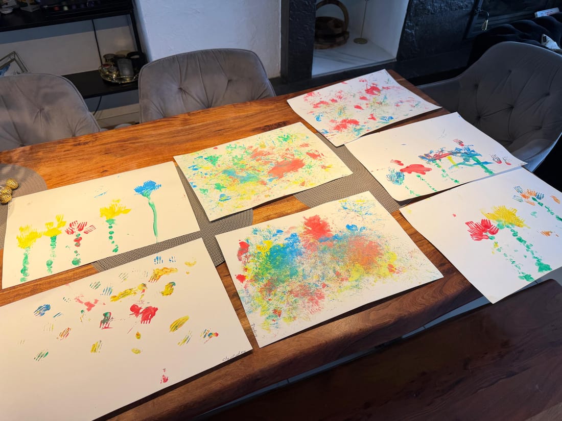 Sieben bunte Kunstwerke aus Gabeldruck-Blumen liegen auf dem Tisch