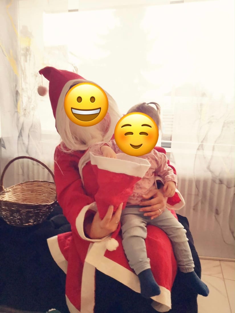 Der Nikolaus hält ein Kind auf dem Schoß, daneben ein Geschenkekorb