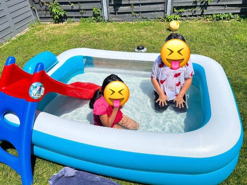 Zwei Kinder planschen an einem Sommertag im aufblasbaren Pool im Garten